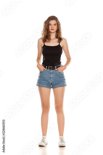 Young pretty woman in short jeans standing on white background
