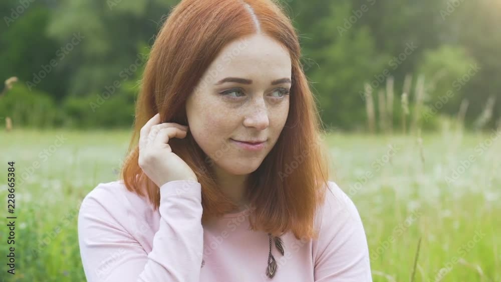Shy beautiful woman looks down up outdoors in summer field, red haired female Shy beautiful woman looks down up outdoors in summer field, red haired female
