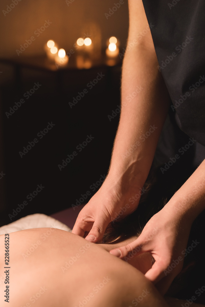 custom made wallpaper toronto digitalMen's hands make a therapeutic neck massage for a girl lying on a massage couch in a massage spa with dark lighting. Close-up. Dark Key