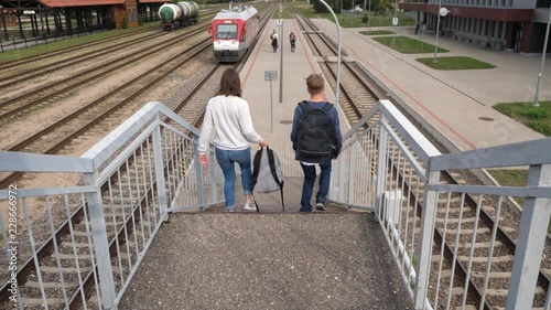 two teenagers with backpacks trying to catch a train and rushing to platform