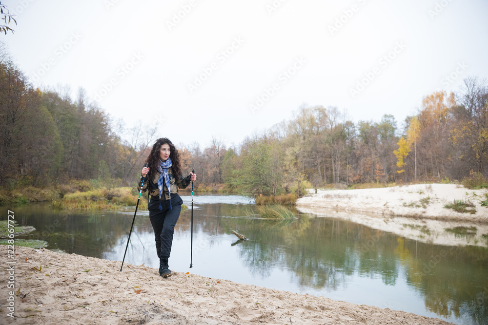 On the banks lake. Curly girl posing in front of lake in forest in autumn