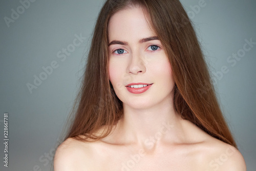 Natural light close up beauty portrait of beautiful blond woman with blue eyes long hair bare shoulders looking at camera