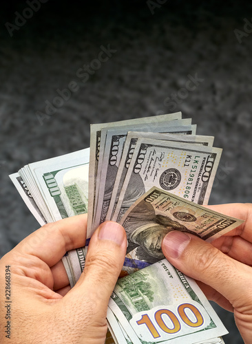Man count the new us dollars or money. New US Dollar bills bundle counting with hand isolated on dark or black background