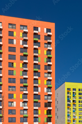 View of the facade of an orange multi-storey residential building. Colorful elements in the design of the building