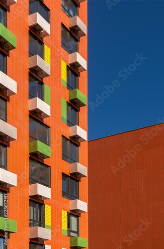 View of the facade of an orange multi-storey residential building. Colorful elements in the design of the building