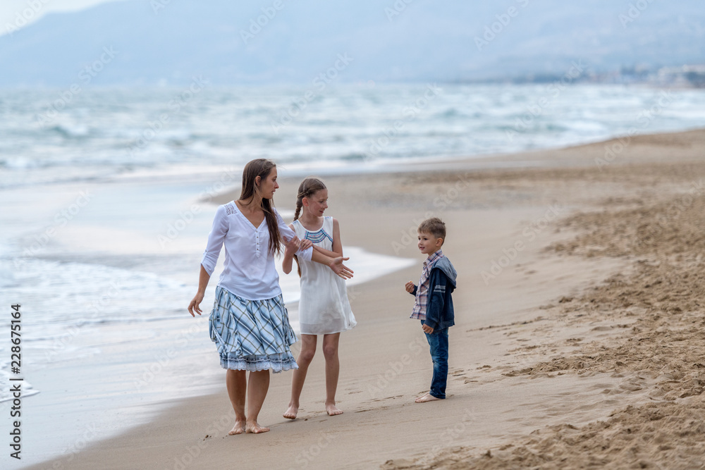 mother and her daughter and son having fun on the beach