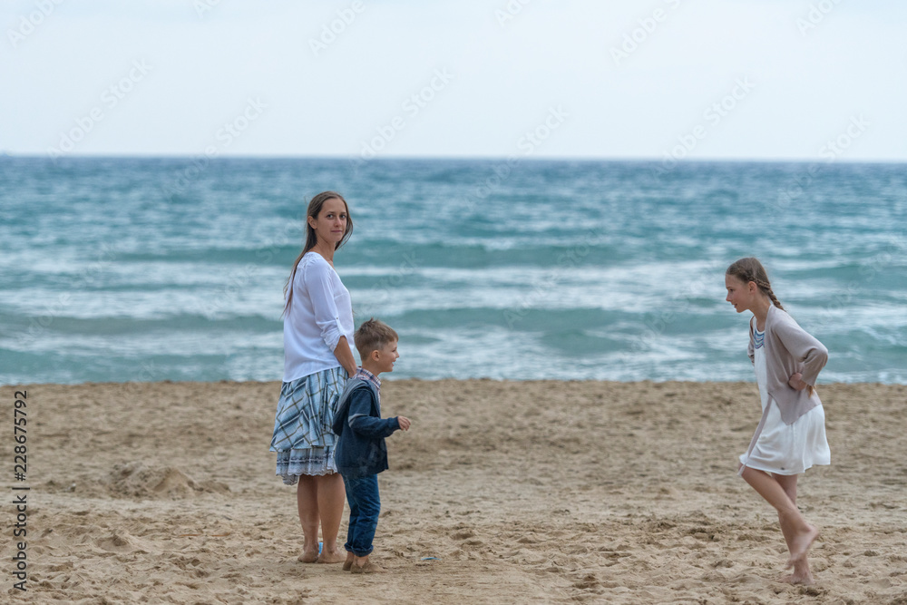 mother and her daughter and son having fun on the beach