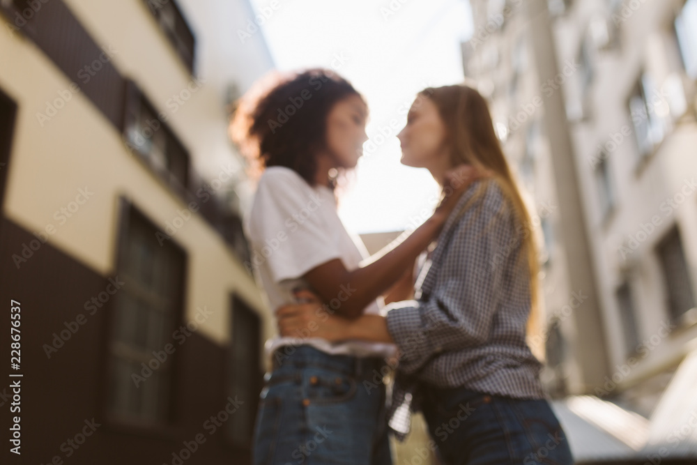 Fuzzy photo of beautiful african american girl with dark curly hair in white T-shirt and pretty girl with blond hair in shirt dreamily spending time together Fuzzy photo of beautiful african american girl with dark curly hair in white T-shirt and pretty girl with blond hair in shirt dreamily spending time together