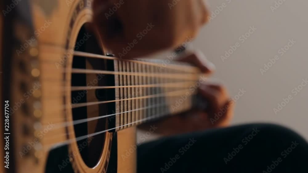 Close up shot of guitarist's hands plays chords on acoustic guitar at home