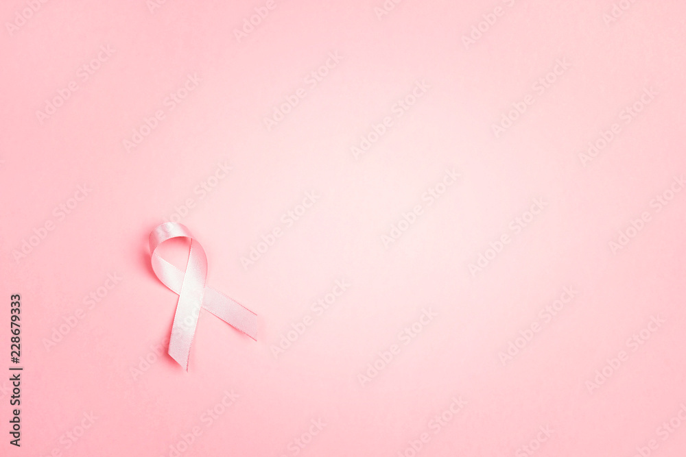 Pink ribbon on pink background with copy space. Breast cancer awareness symbol. Pink ribbon on pink background with copy space. Breast cancer awareness symbol.