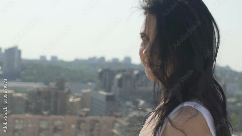 Beautiful attractive female turns around on city land scape, woman looks camera Beautiful attractive female turns around on city land scape, woman looks camera