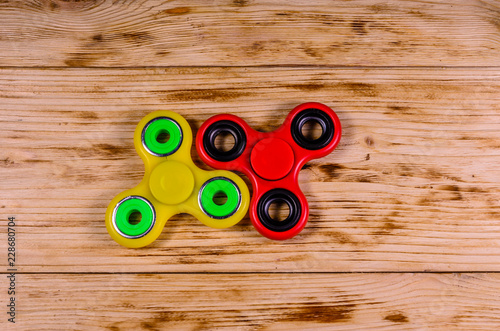 Two fidget spinners on wooden desk. Top view