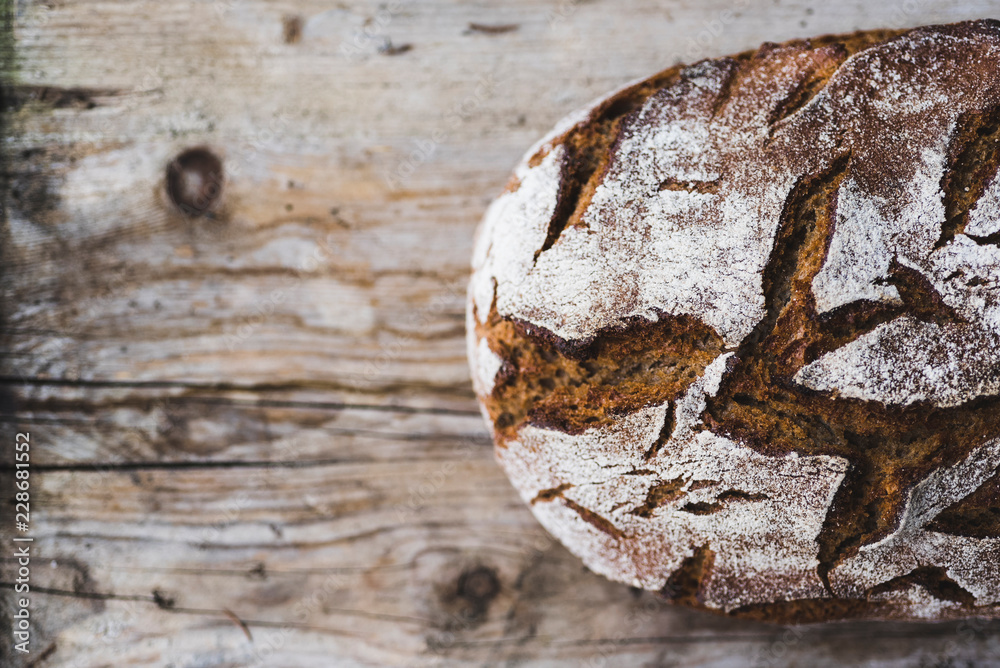 Loaf of brown bread on wood, partial view