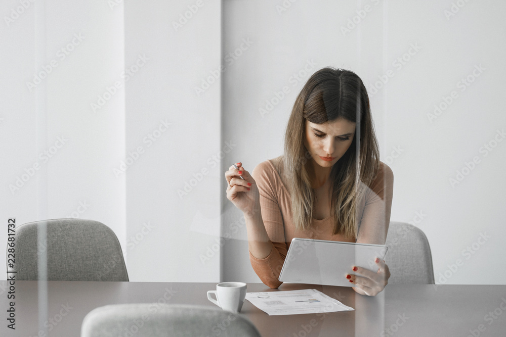 Pretty businesswoman sitting at meeting room and working on her tablet. Pretty businesswoman sitting at meeting room and working on her tablet.