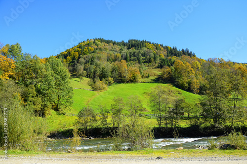 Autumn mountain landscape on a sunny clear day. Blue sky, mountain river and forest.