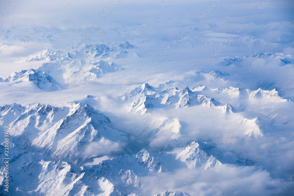 Fototapeta premium winter mountains in the clouds from aircraft