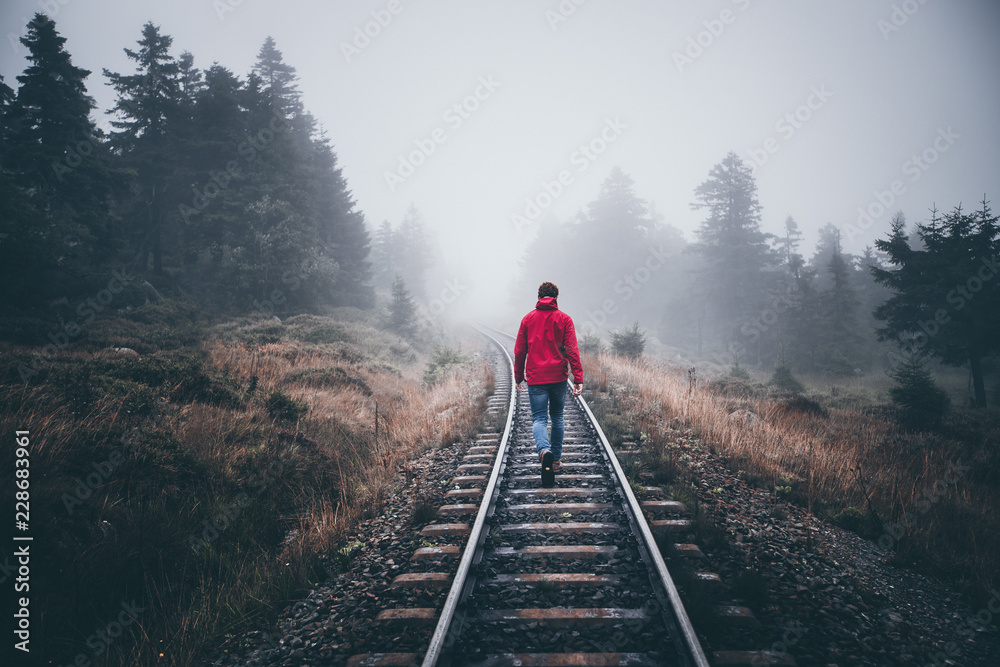 Wanderer läuft in roter Jacke über Schienen im Harz - obrazy, fototapety, plakaty 