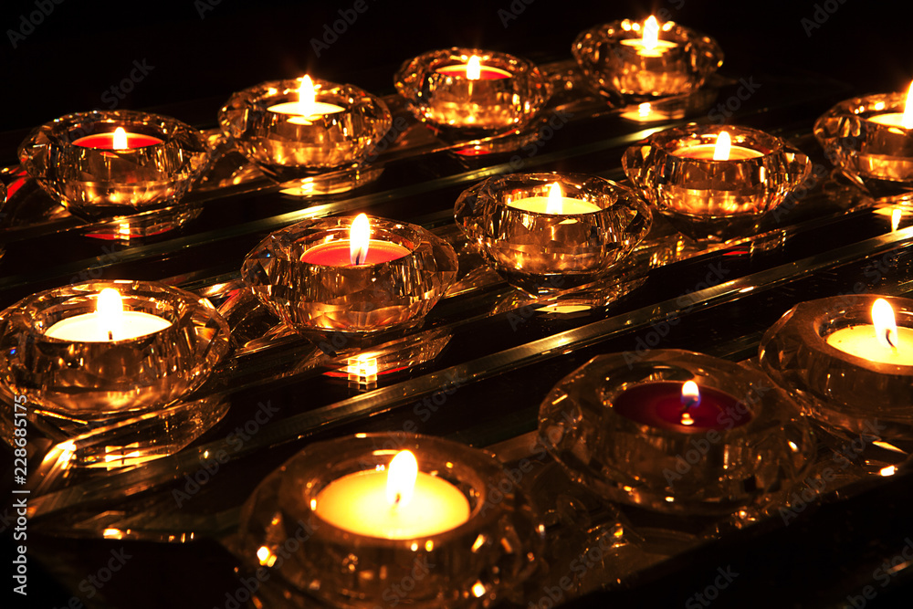 Coloured tealight candles in with flickering flames in crystal holders - obrazy, fototapety, plakaty 