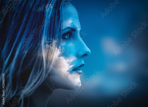 Double exposure of young woman and cloudy sky.
