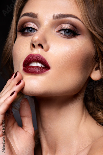 Close-up portrait of beautiful woman with bright make-up and dark red lips