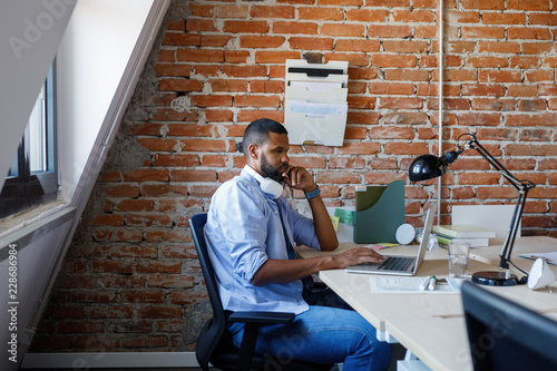 Casual African businessman working on his laptop at modern office.