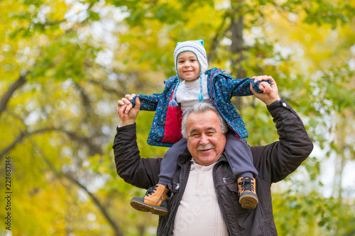 Playful grandfather spending time with his grandson in park on sunny day photo
