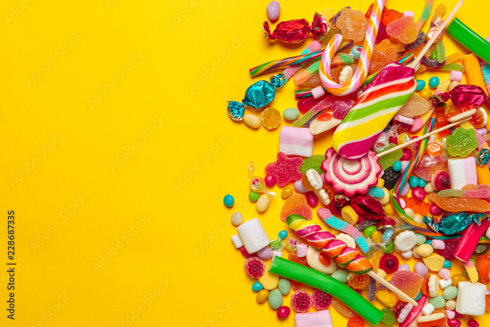 colored candies on yellow background colored candies on yellow background