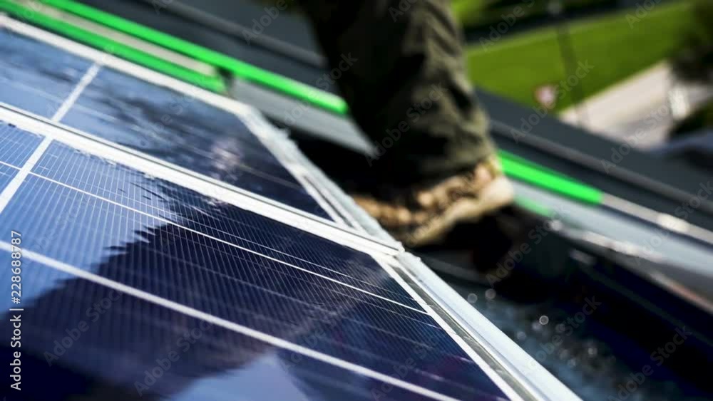 Worker is washing solar panels on the roof