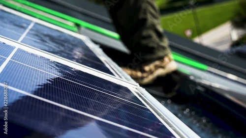 Worker is washing solar panels on the roof
