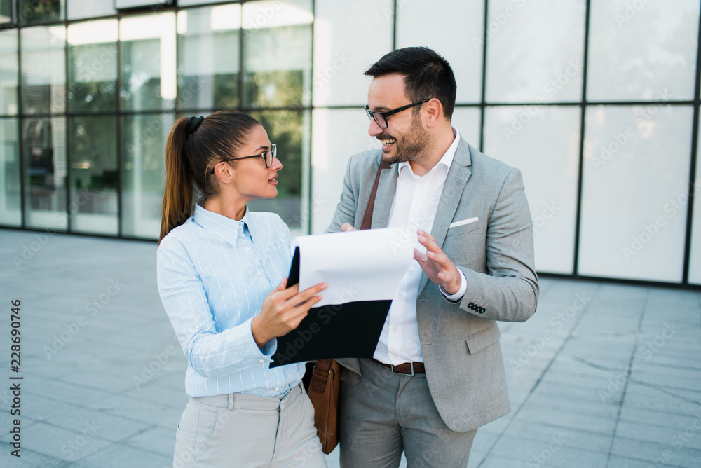 Business people smiling, team of two attractive successful young businesswoman and businessman working together, looking at business chart and discussing business plan. Business people smiling, team of two attractive successful young businesswoman and businessman working together, looking at business chart and discussing business plan.