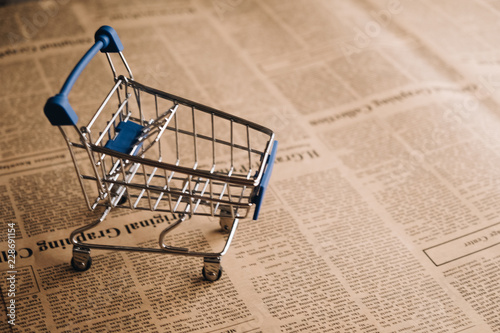 Empty shopping cart on newspaper background with copy space for text, Shoping online concept.