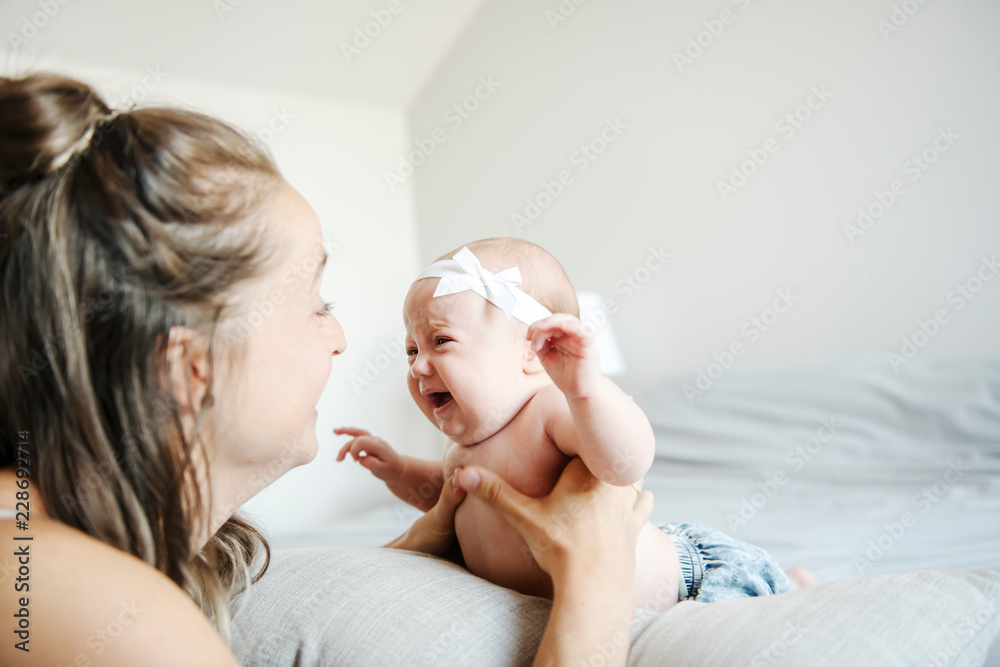 Portrait of a beautiful mother with her 2 month old baby in the bedroom Portrait of a beautiful mother with her 2 month old baby in the bedroom