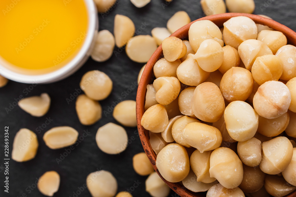 delicious macadamia nuts on a dark stone background delicious macadamia nuts on a dark stone background