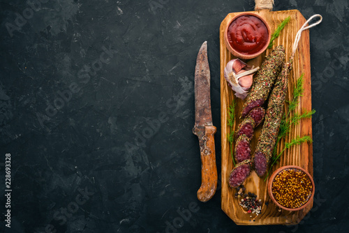 Sausage Fuet. Salami with spices. On a black background. Top view. Free space for your text. photo