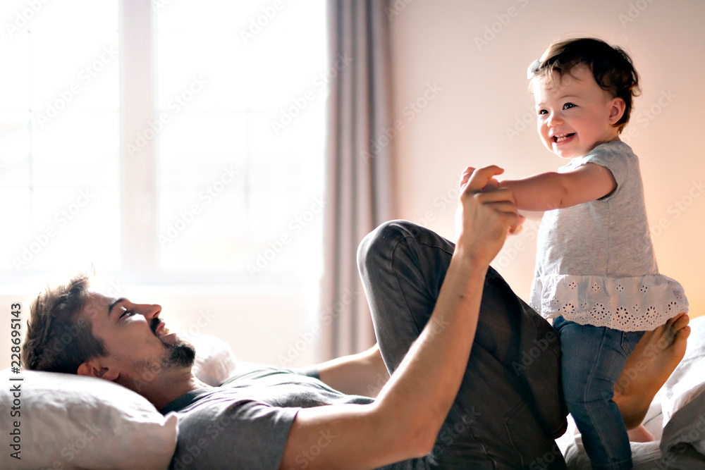 Fototapeta premium Young father with child girl on bed at home