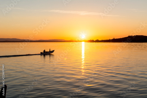 Un motoscafo solca le acque del lago al tramonto