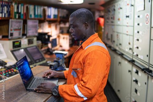 African marine engineer officer in engine control room ECR. Seamen's work. He works at the computer photo