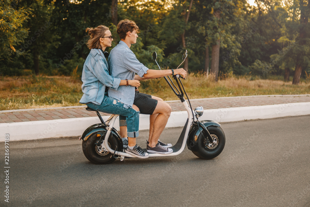 Lovely young couple driving electric bike during summer Modern city life and transportation Lovely young couple driving electric bike during summer Modern city life and transportation