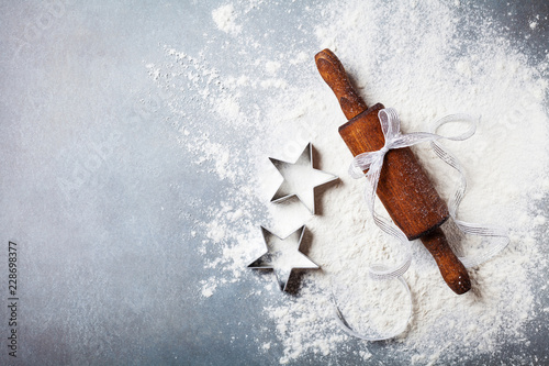 Bakery background for cooking christmas baking with rolling pin and scattered flour on kitchen table top view.