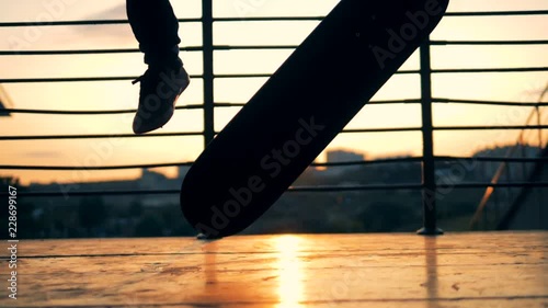 Skater fails doing trick. Person jumping on a skateboard on a sunset background, slow motion. photo