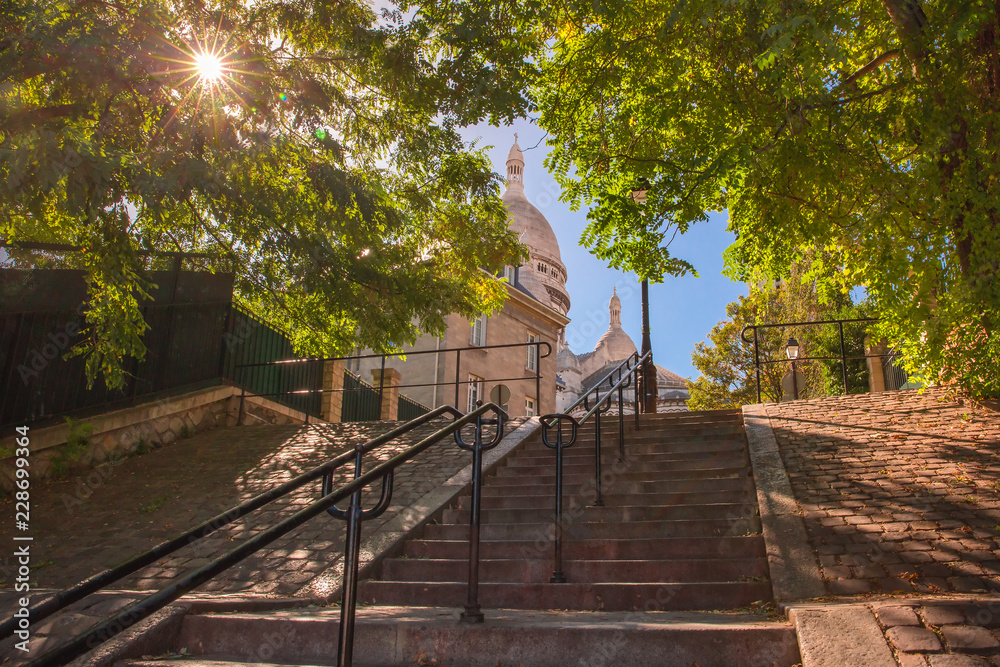 Typical sunny Montmartre staircase to Sacre-Coeur in the morning and sunlight coming through the trees, quarter Montmartre in Paris, France