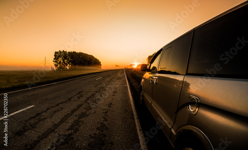 A minibus standing on the roadside in a peaceful misty summer morning, in anticipation of a journey to far-away places.
