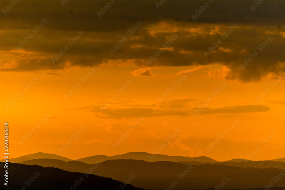 Un tramonto arancione intenso sui monti Martani dopo un temporale