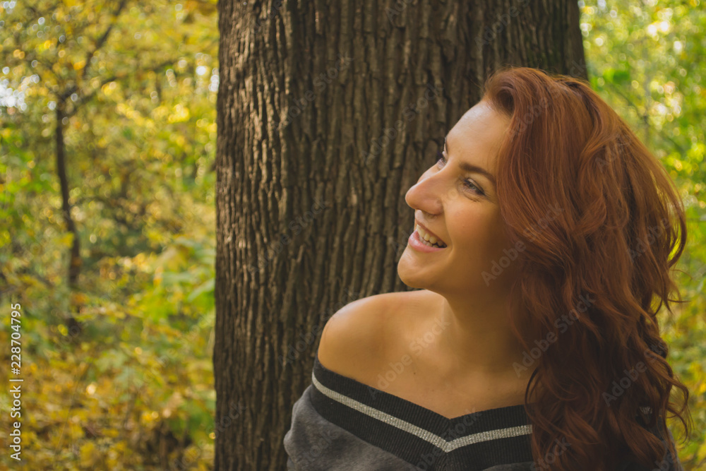 Naklejka premium Redhead woman in the park at autumn.