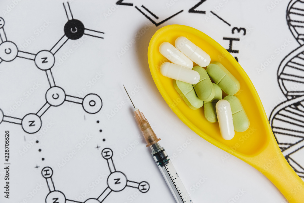 Assortment of Pills, Tablets and Capsules in Yellow Spoon, Syringe on White Background with Chemical Formula. Assortment of Pills, Tablets and Capsules in Yellow Spoon, Syringe on White Background with Chemical Formula.