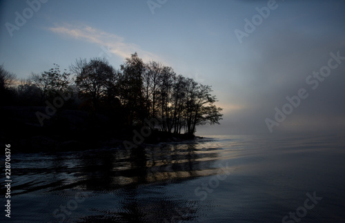 Lake Malaren in stockholm an early cold and foggy autumn day, shilouettes and reflextion in the calm water