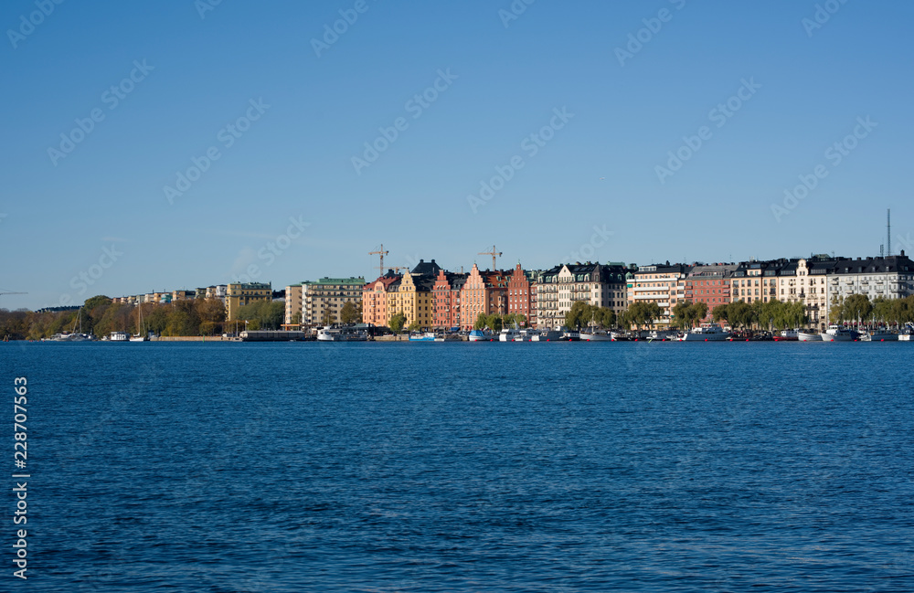 Stockholm water front with landmarks, boats an autumn day with blu sky and sea, orange and red leafs.