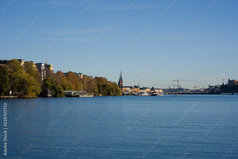 Stockholm water front with landmarks, boats an autumn day with blu sky and sea, orange and red leafs.