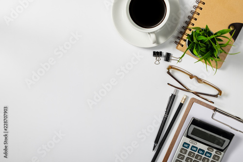 View from above.eye glasses,pen,notebook,calculator, and cup of coffee on white office desk with copy space.
