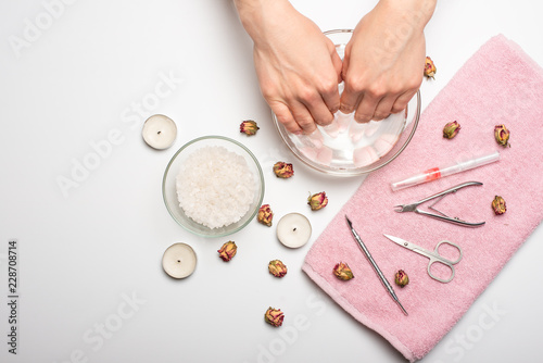 Manicure - the girl herself does, watching the nails with the help of a tool on a white background. Concept of beauty salons and nail care photo